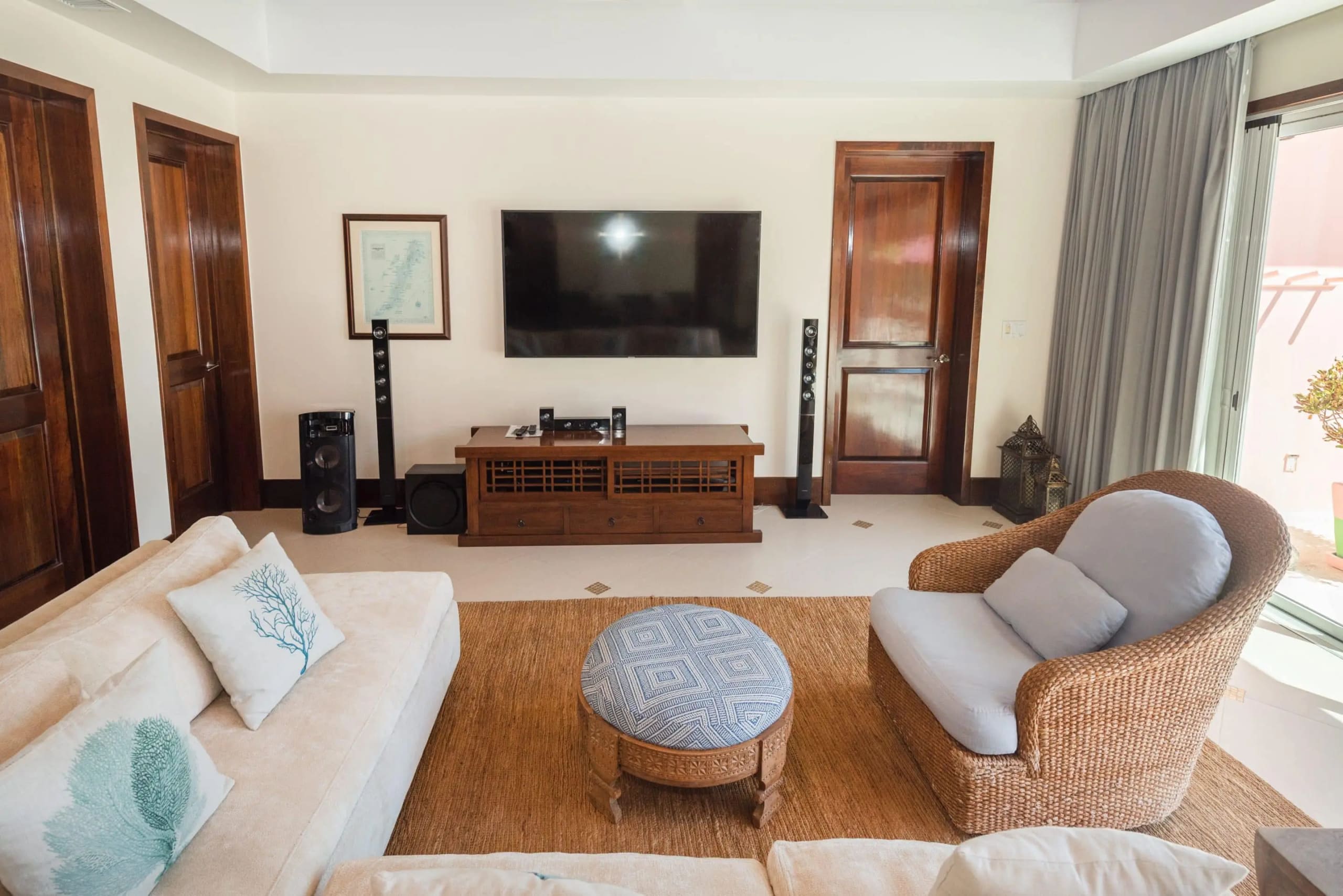 Living room with sofa, woven armchair, and media wall opening to the terrace