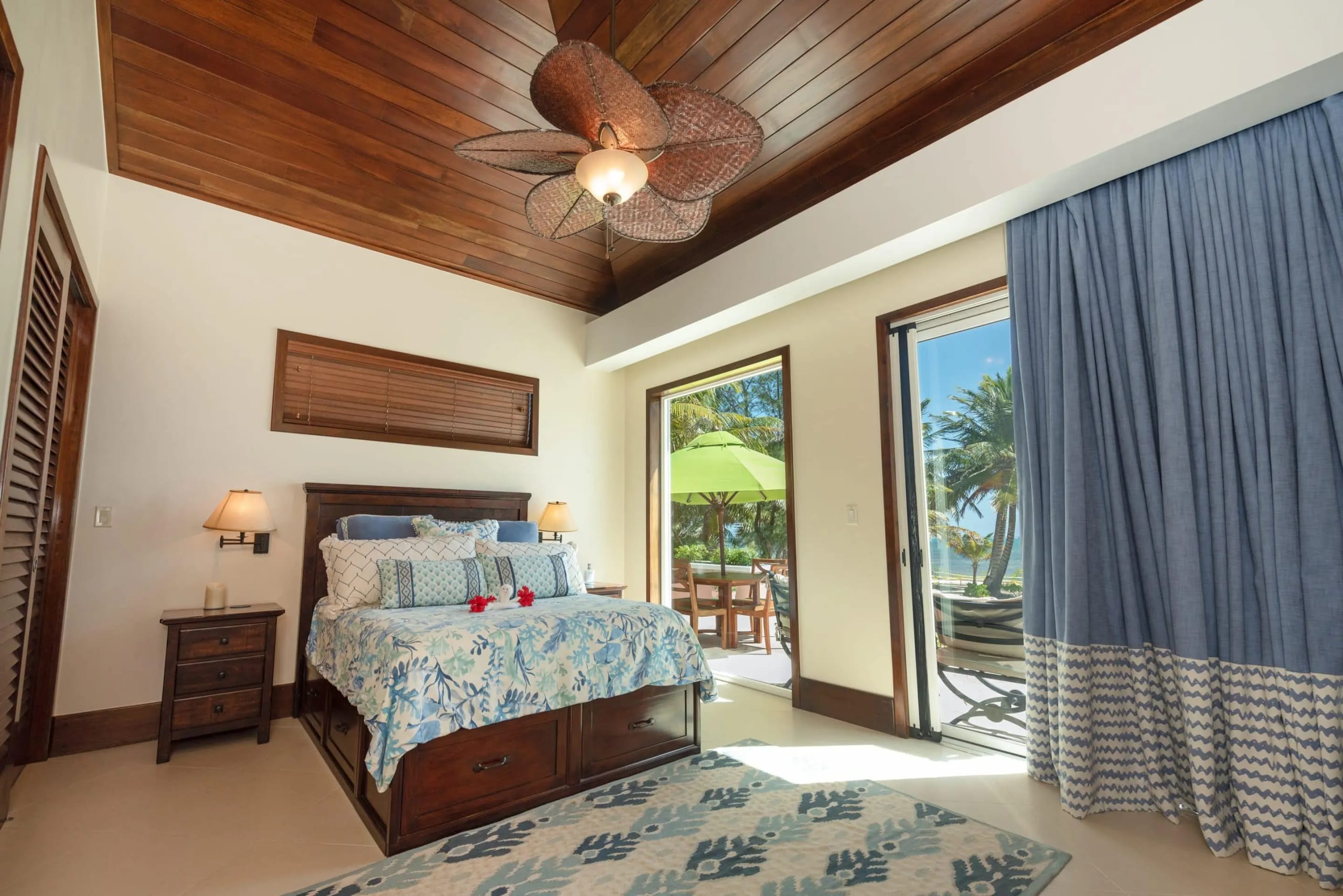 Suite 1 bedroom with tropical bedding, ceiling fan, and doors onto the pool terrace