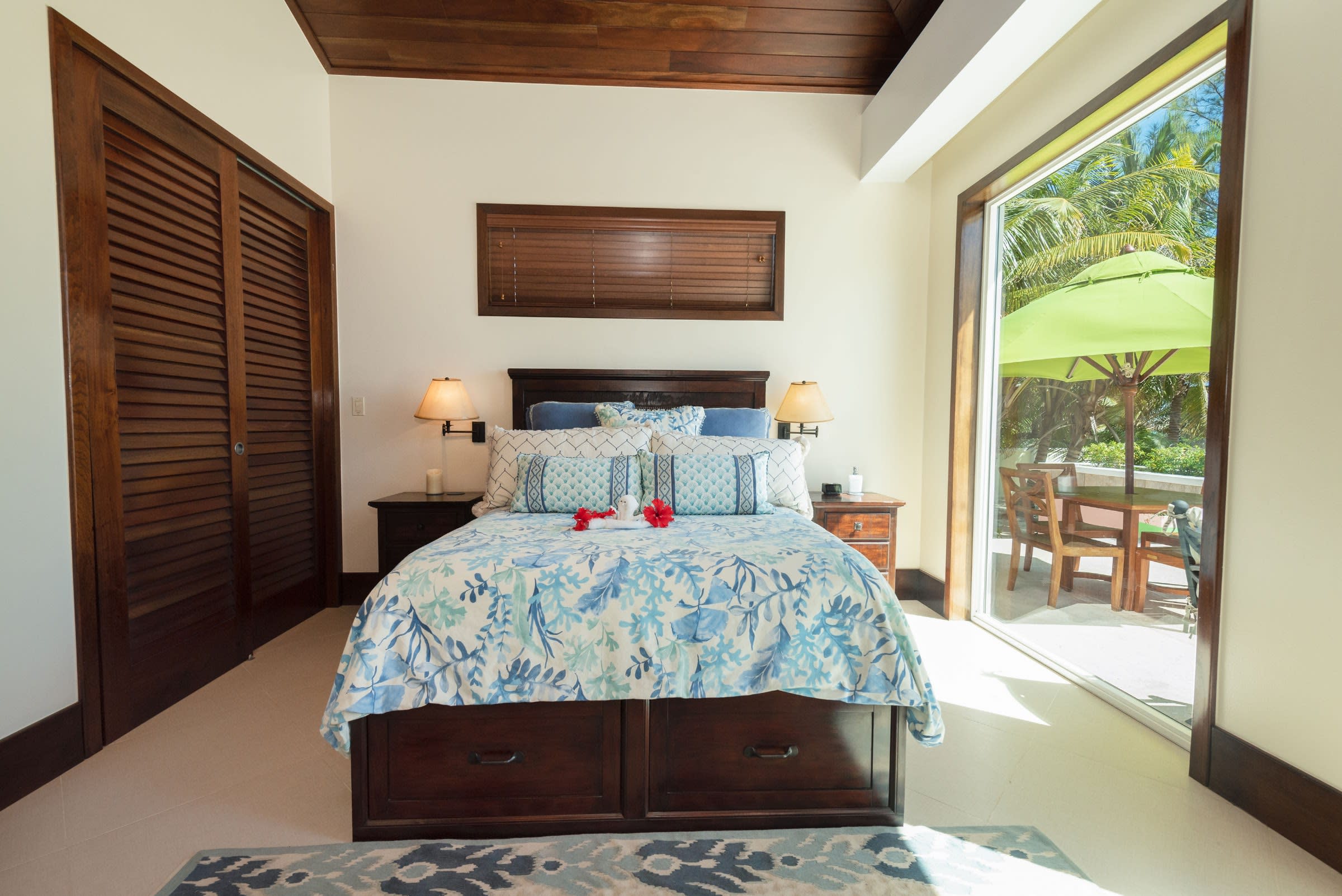 Serene suite bedroom with glass doors opening directly to a furnished oceanside terrace.