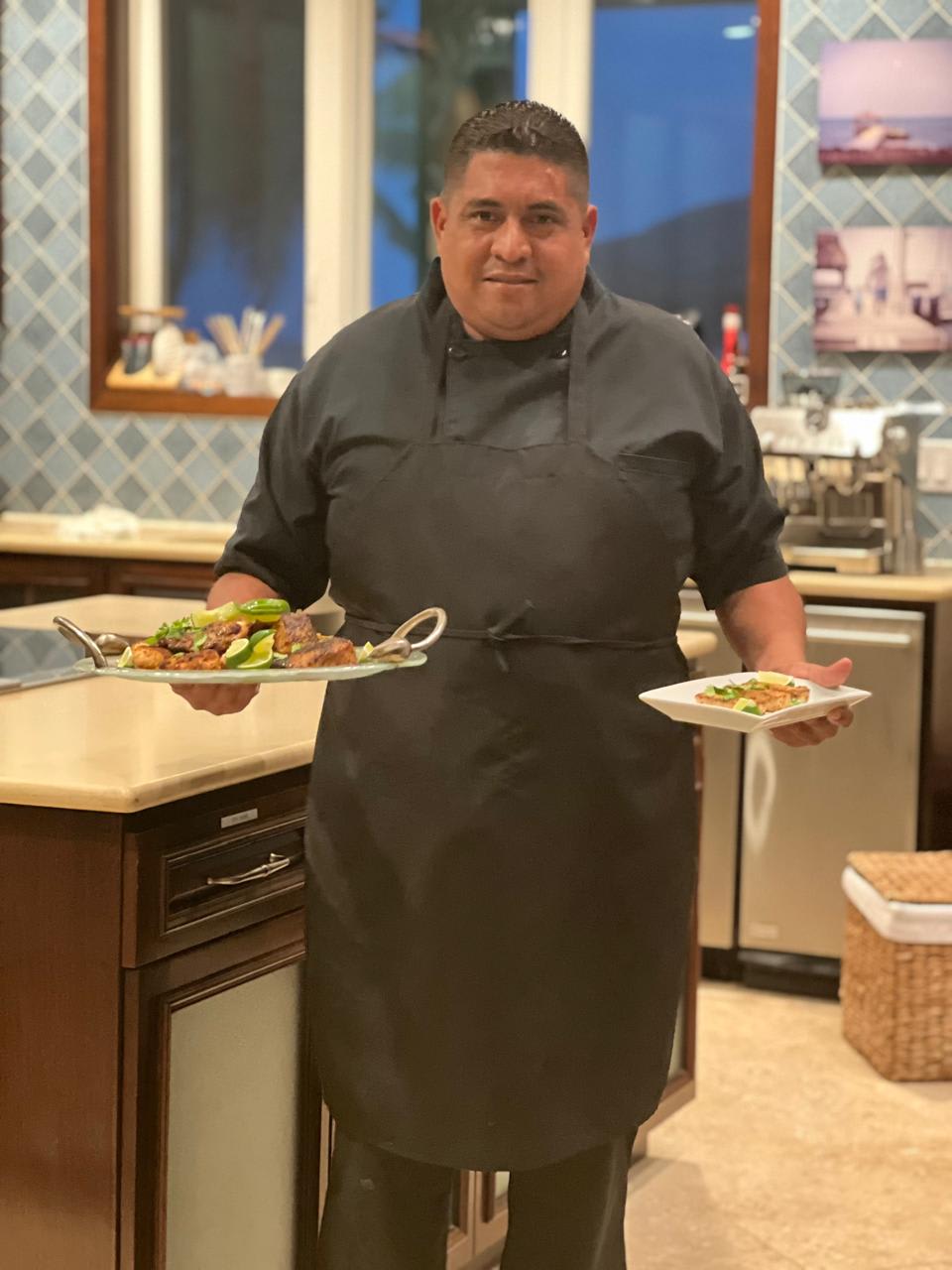 Chef Marvin carrying plated dishes with a smile