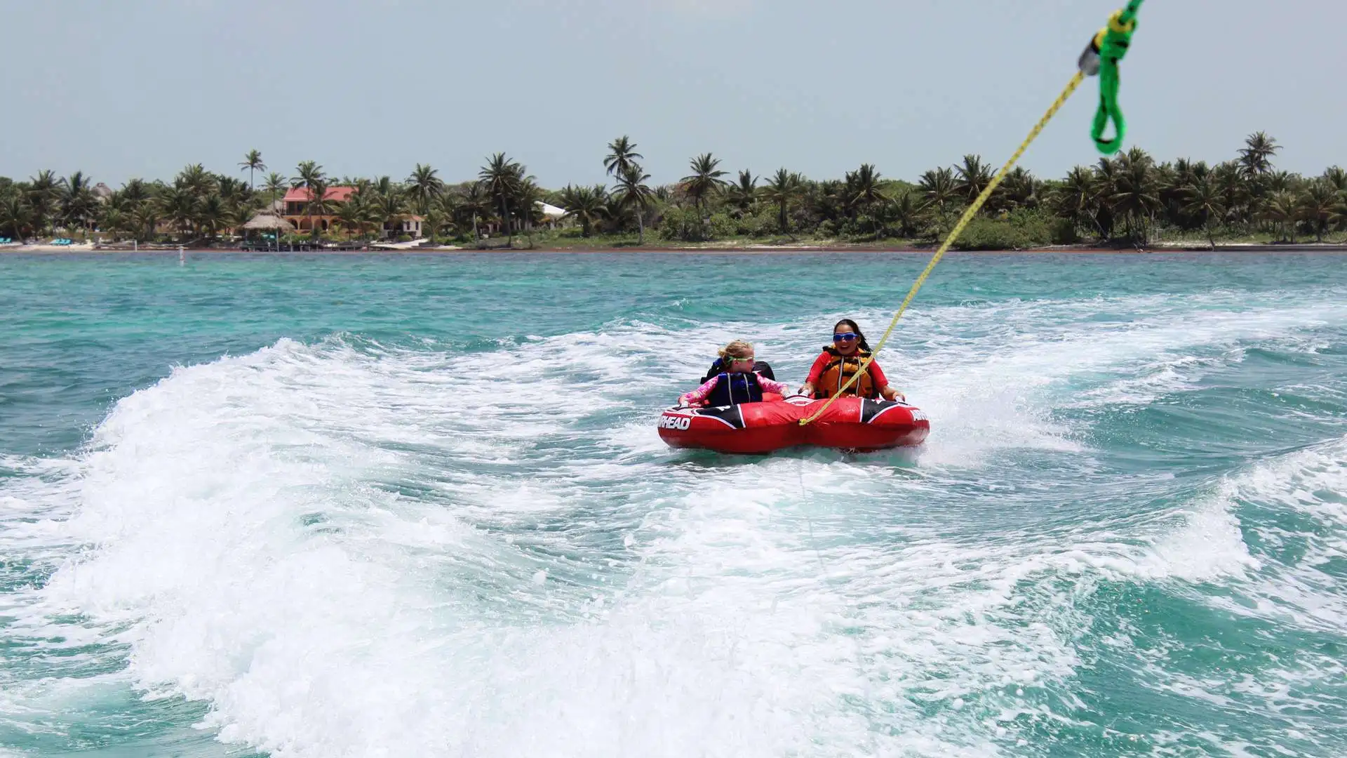 Kids tubing behind a boat on clear water