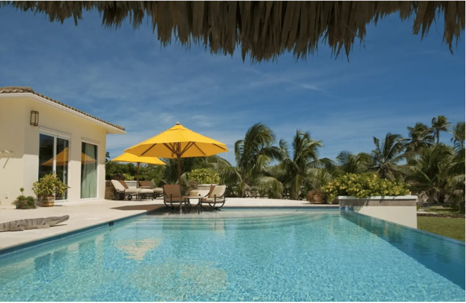 Infinity pool with yellow umbrellas beside the villa
