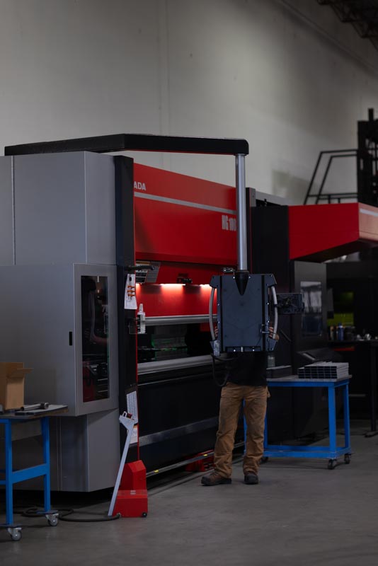 Press brake forming a long aluminum panel with digital angle control.