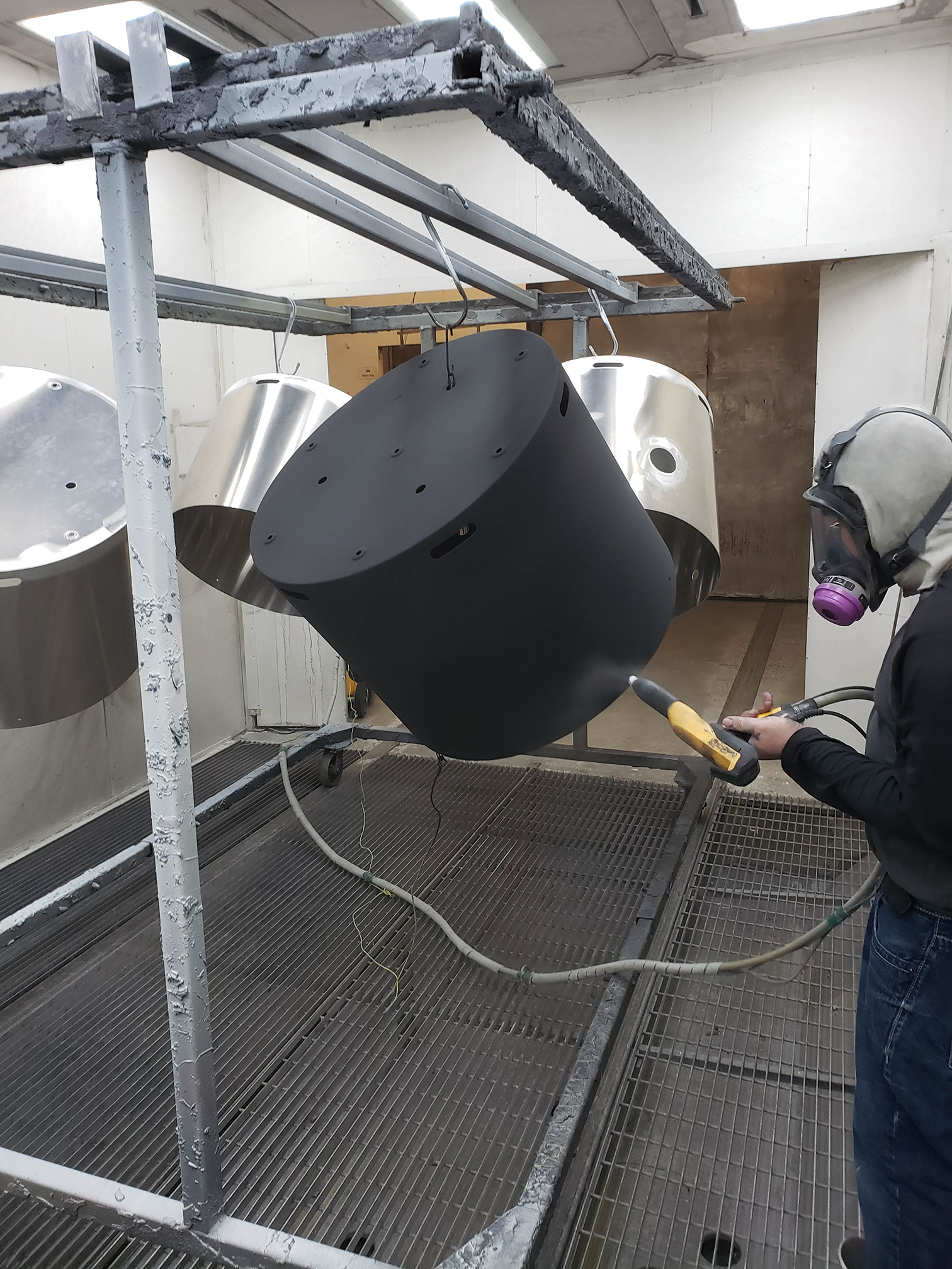 Powder coating booth finishing a batch of fabricated aluminum components.