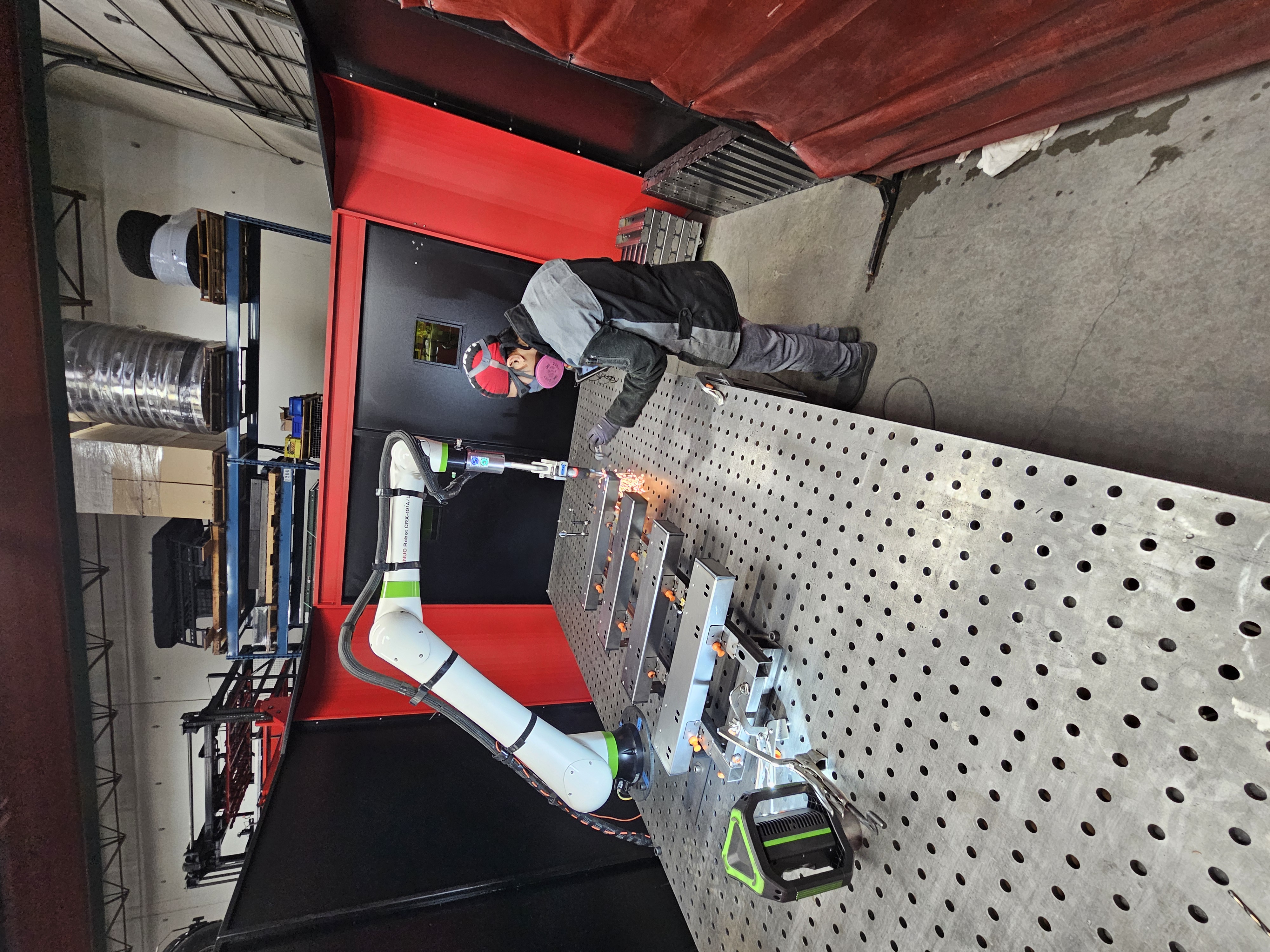 Fanuc robotic arm equipped with a LightWELD torch inside FortiFab's automation cell.