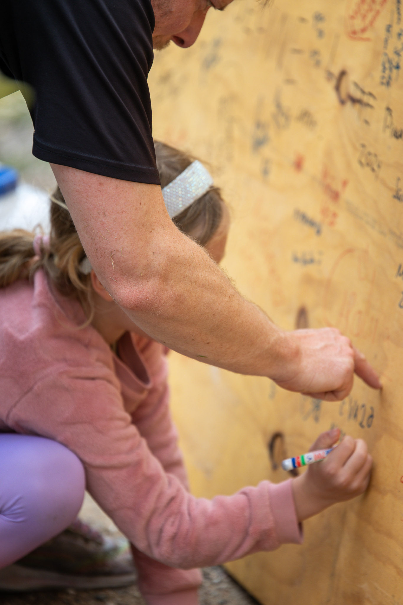 En ældre deltager vejleder et barn i hvordan den traditionsrige platte skal signeres efter målgang på 5. etape.