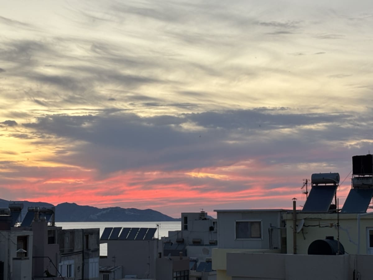 Beautiful sunset over Crete with warm orange and pink hues reflecting across the calm water
