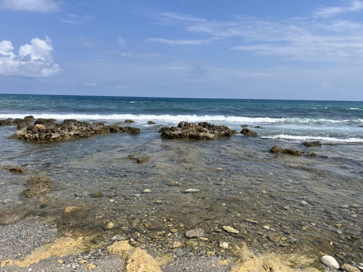 Rocky coastline beach in Greece with dramatic cliffs and the sparkling Mediterranean Sea