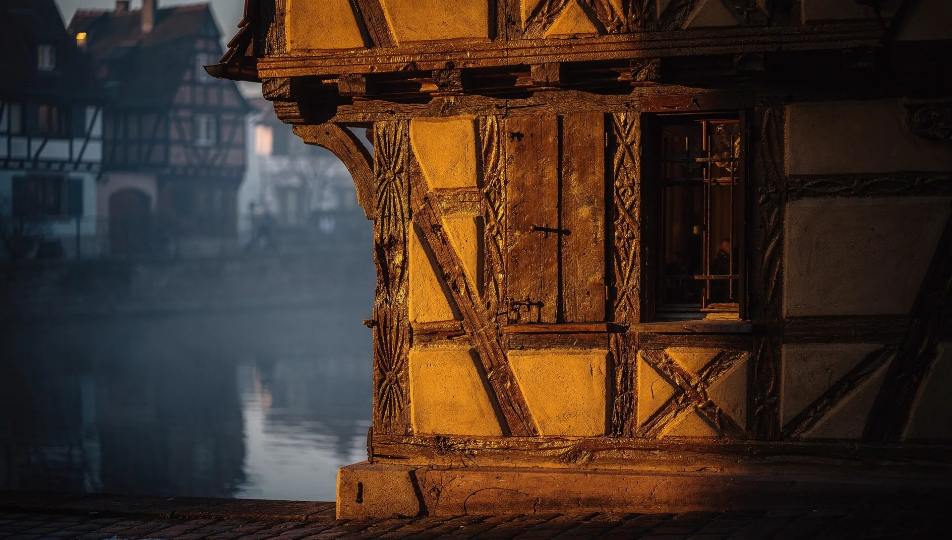Façade à colombages alsacienne au crépuscule évoquant l'ancrage régional de la Mutuelle Complémentaire d'Alsace