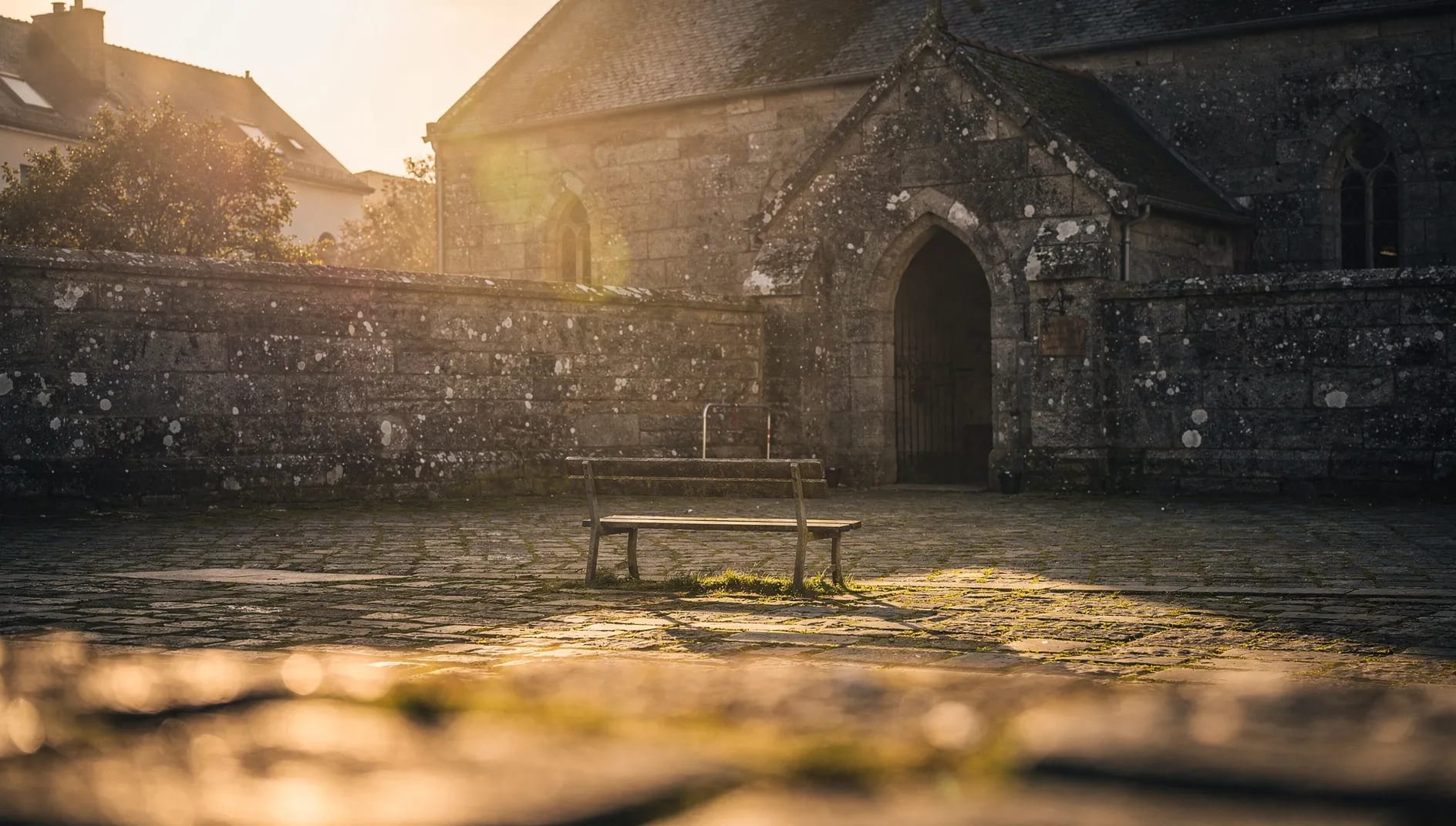 Cour d'école et chapelle bretonne en pierre au crépuscule évoquant l'histoire centenaire de MUTEC 22 à Saint-Brieuc