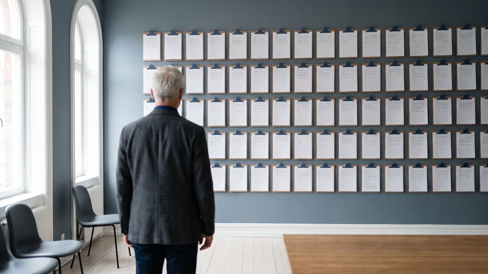Senior operator reviewing a wall of clipped engagement case-study briefs in La Boétie's studio room