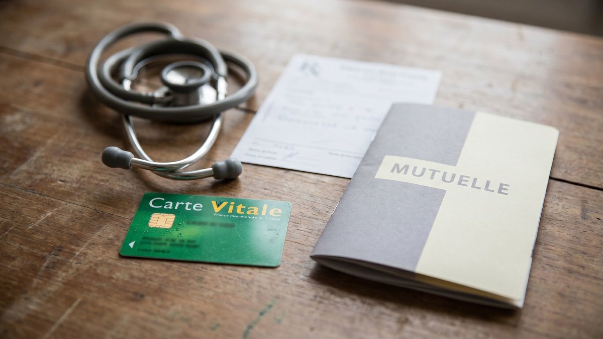 French Carte Vitale healthcare card with a mutuelle booklet and stethoscope on a wooden table