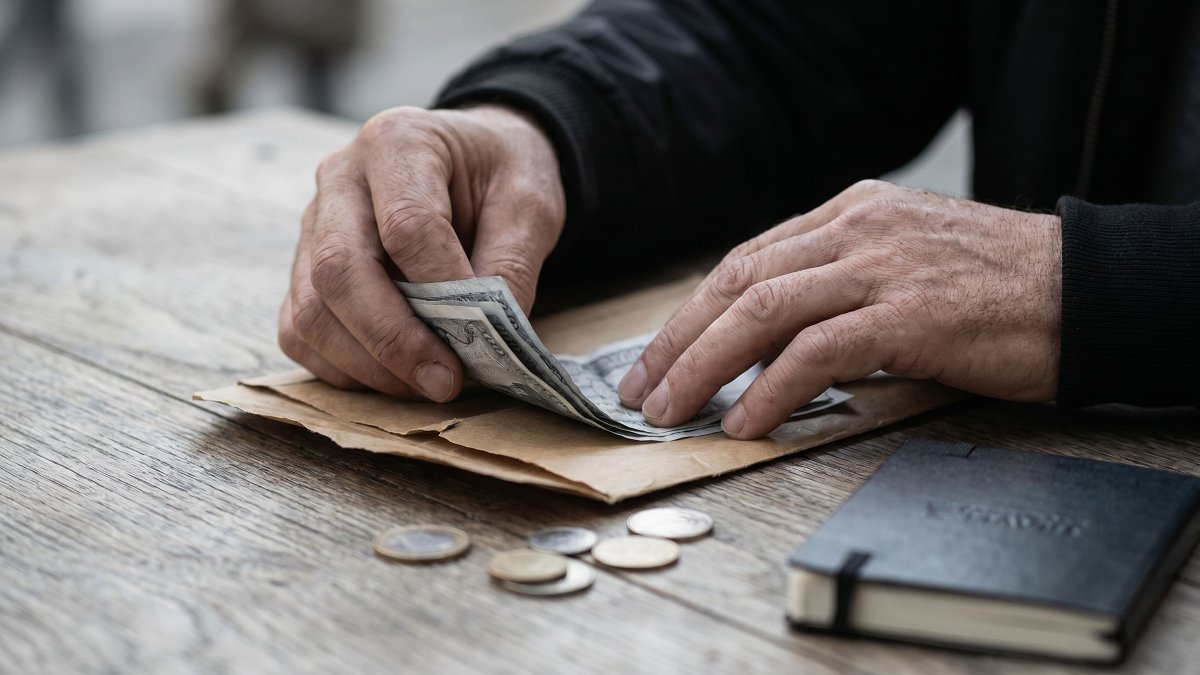Hands placing cash into a shared envelope for a group trip kitty