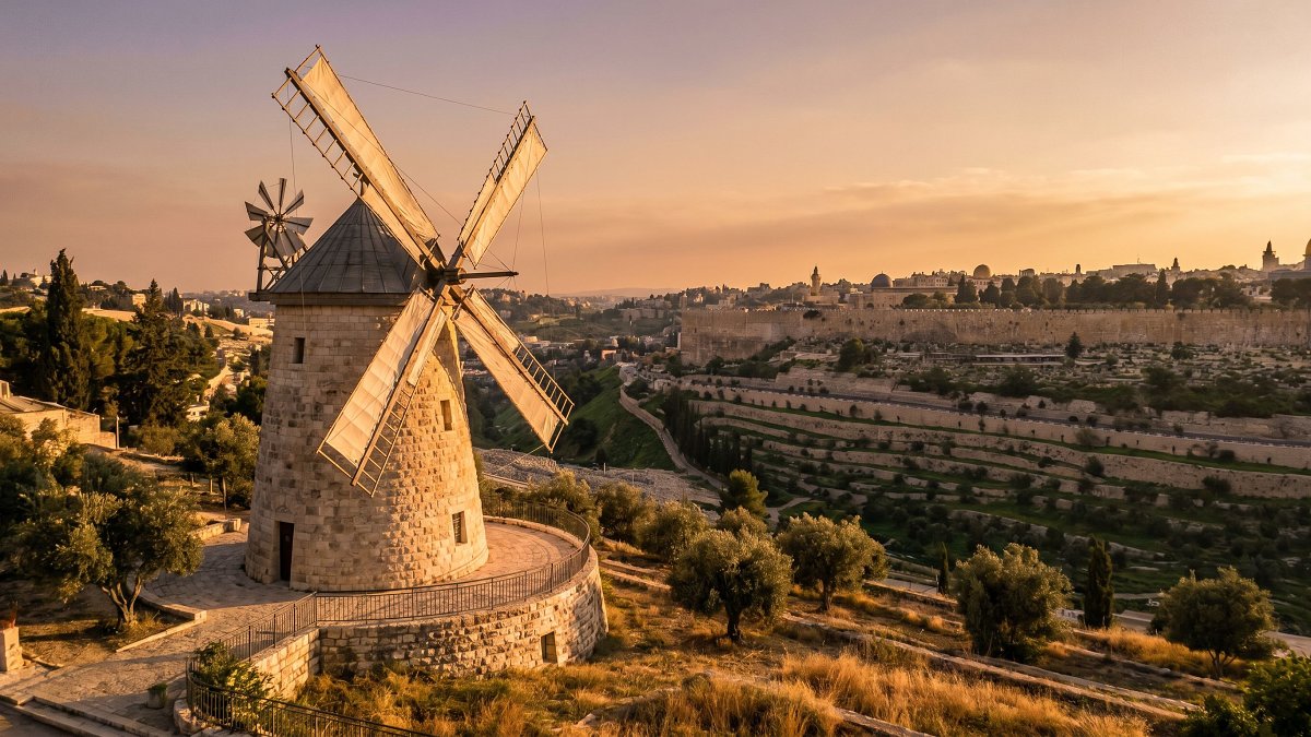The Montefiore windmill at Mishkenot Shaananim at golden hour with the Old City ramparts beyond