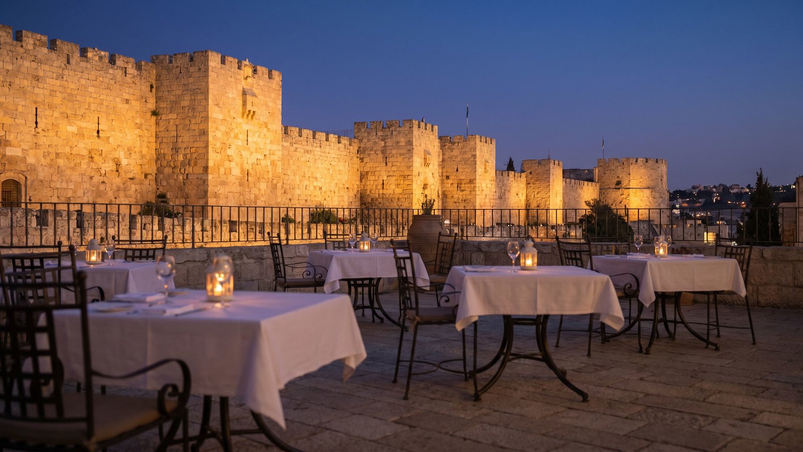 Jerusalem Old City walls glowing gold at dusk above a quiet kosher dining promenade