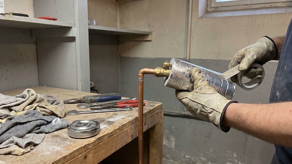 Pose d'une coquille isolante sur un coude de réseau de chauffage