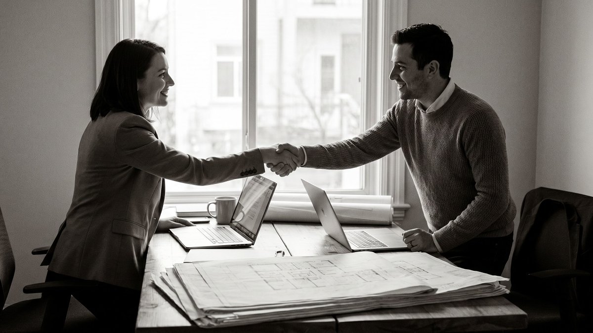Two professionals shaking hands during a technical project handover
