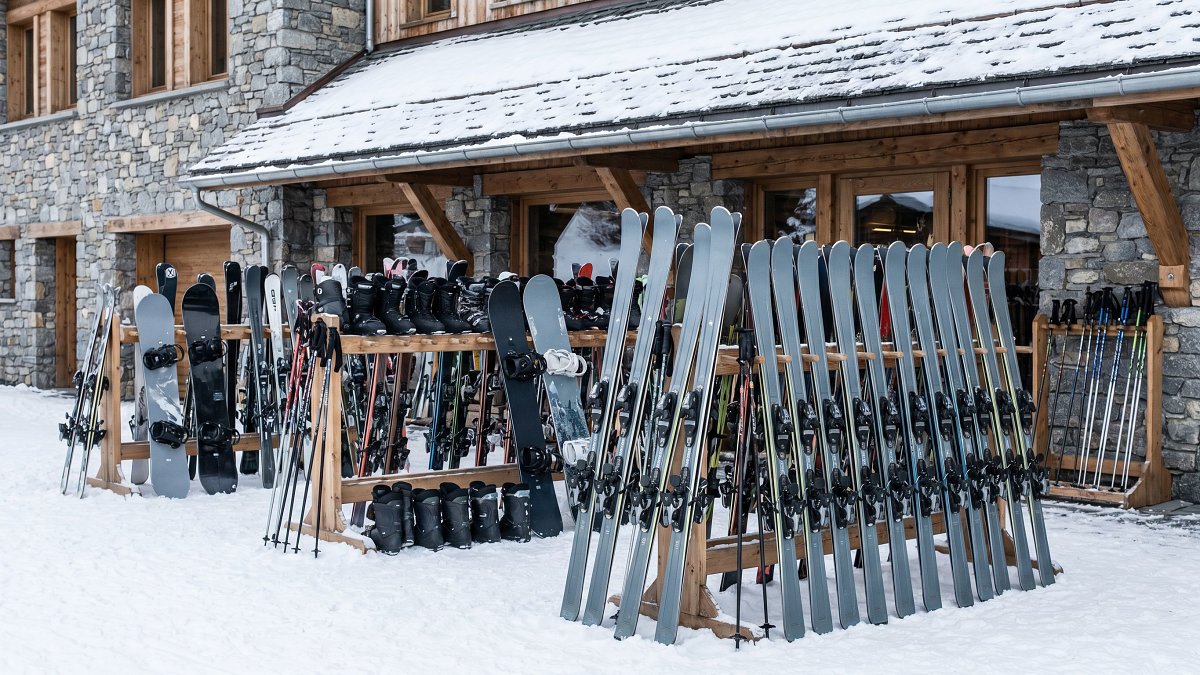 Ski and snowboard rental gear lined up outside a mountain rental shop