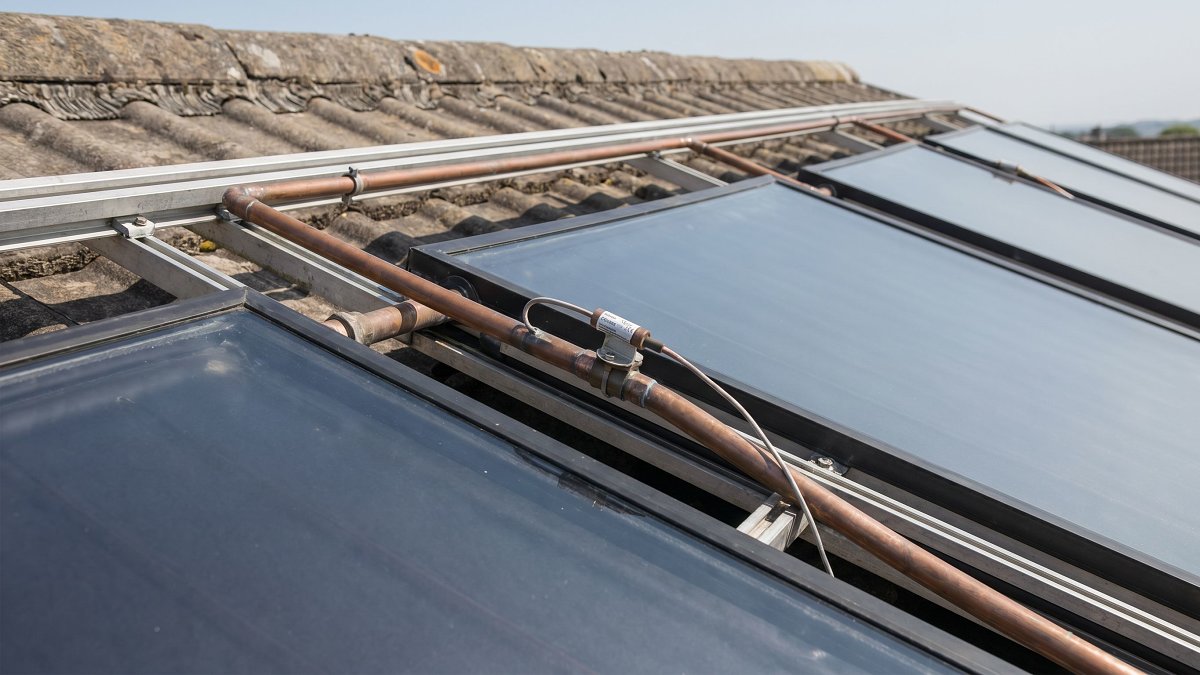 Capteurs solaires thermiques vitrés et tuyauterie cuivre d'un chauffe eau solaire individuel sur un toit résidentiel