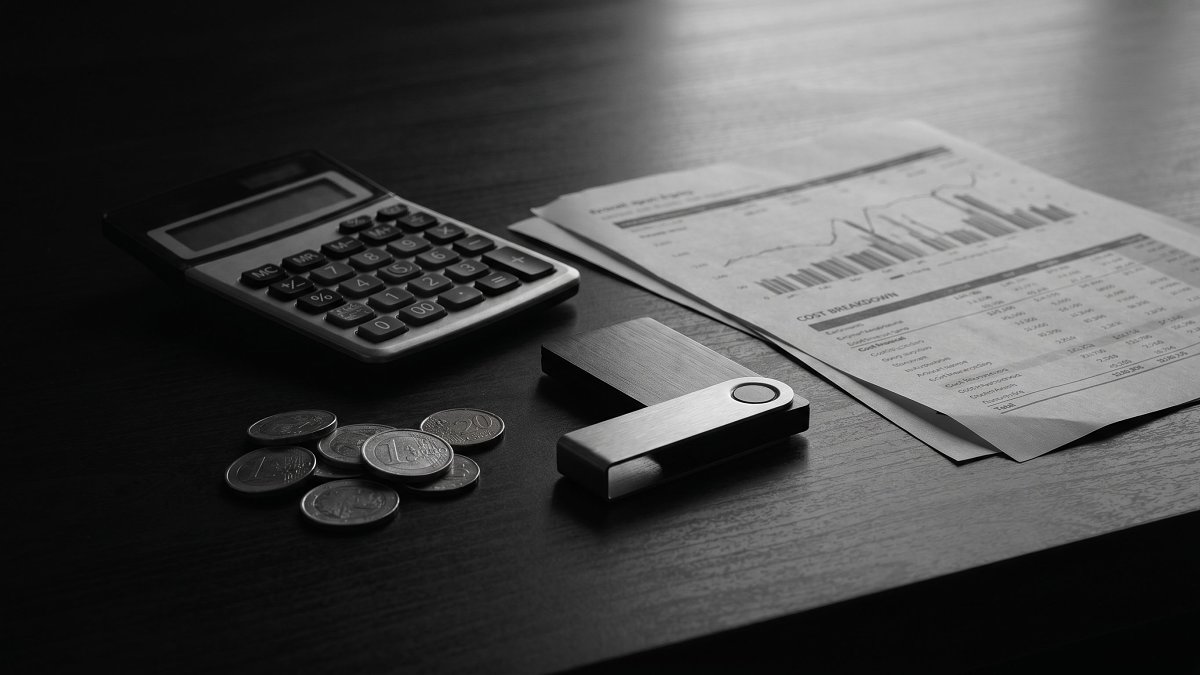 Calculatrice, pièces en euros et portefeuille matériel illustrant la reconstitution des frais réels des cryptoactifs