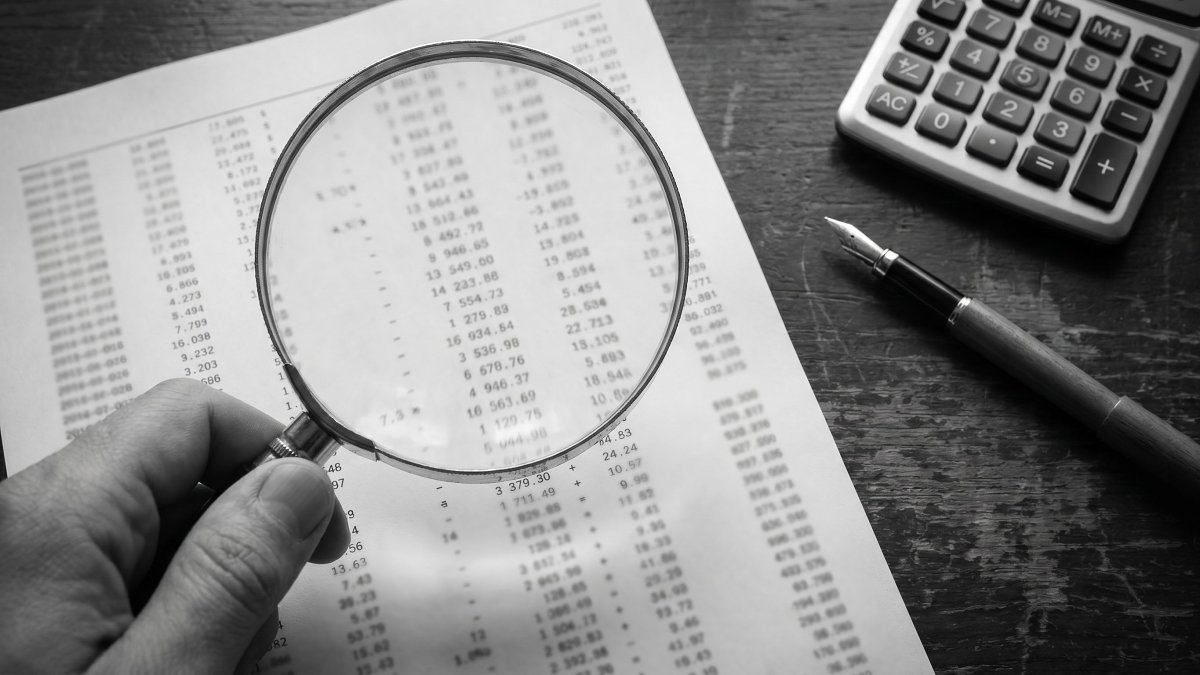 Loupe posée sur un relevé financier détaillé, symbole de l'analyse des frais réels et du rendement net
