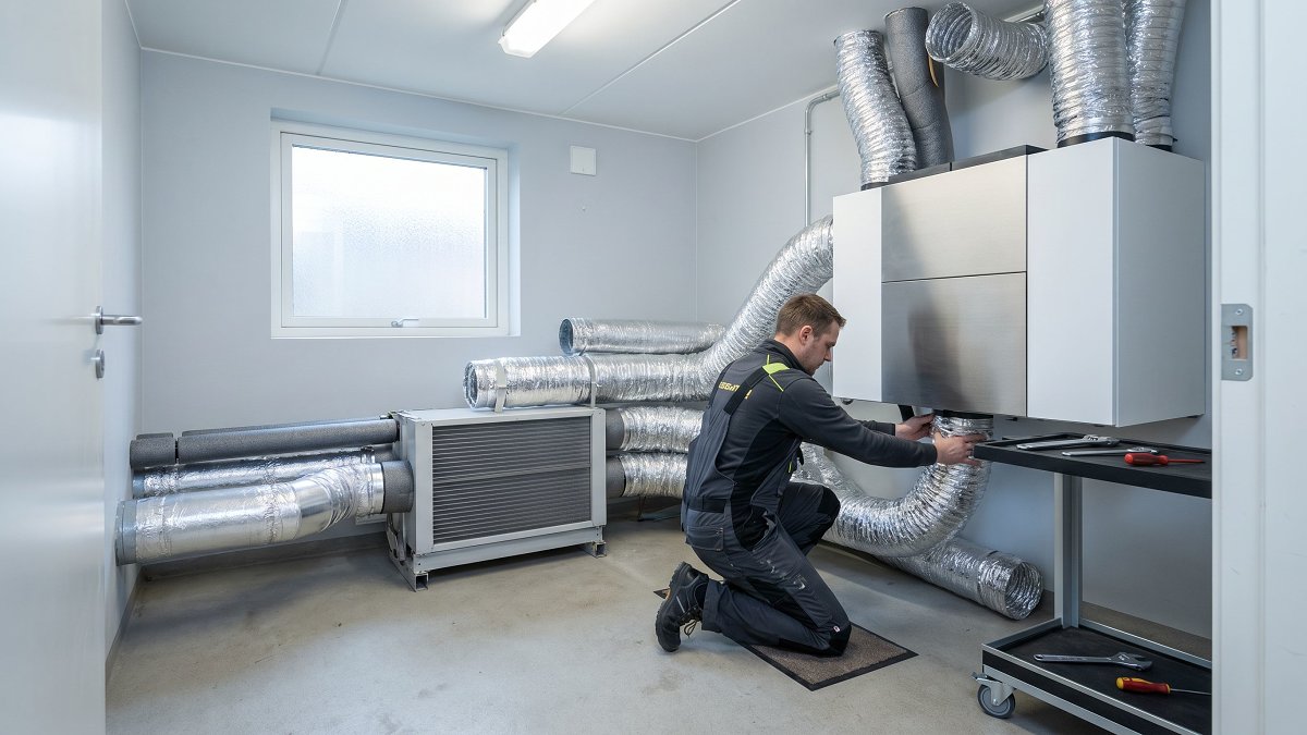 Technicien installant une VMC double flux dans l'espace technique d'une maison