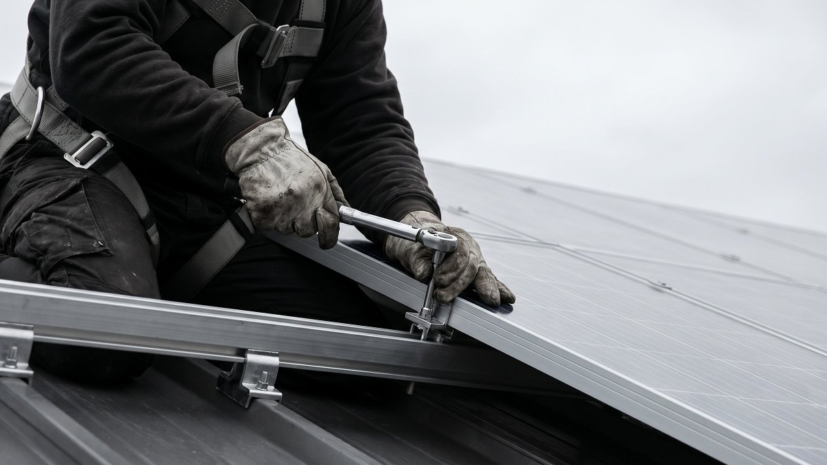 Installateur certifié posant un panneau photovoltaïque sur un rail de toiture