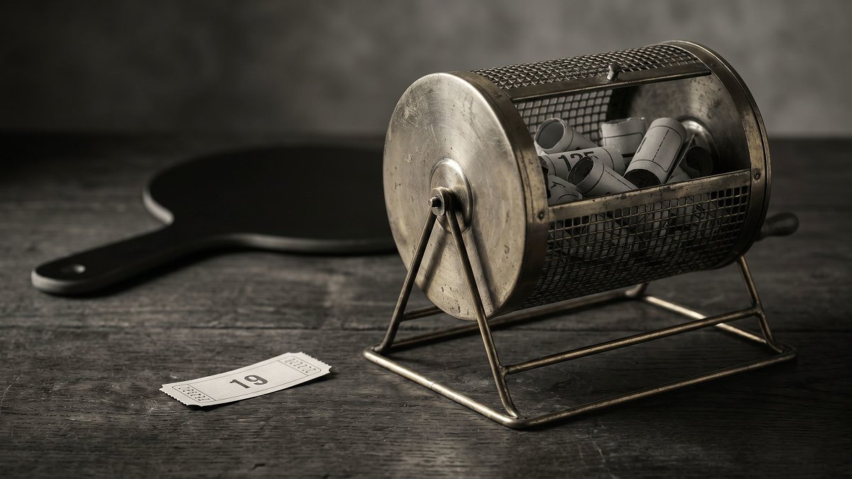 A brass tombola raffle drum and a single numbered ticket beside an auction bidding paddle