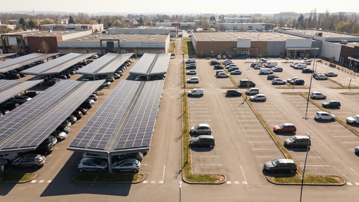 Parking commercial à moitié couvert d'ombrières photovoltaïques conformes à la loi APER