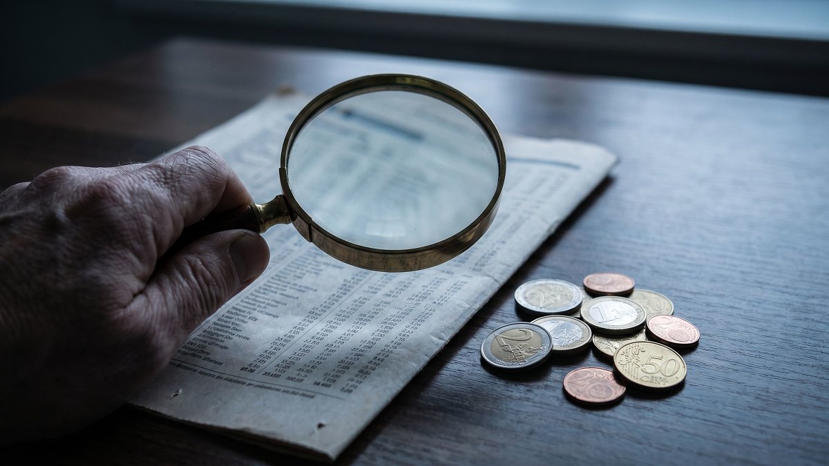 Loupe sur une grille de frais et une pile de pièces qui diminue, illustrant les frais réels d'un FCPI