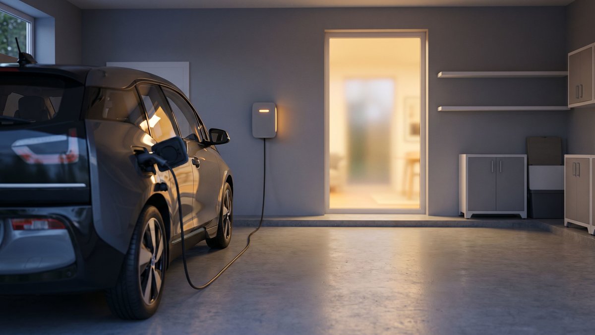 Borne de recharge murale et voiture électrique en charge dans le garage d'une maison individuelle