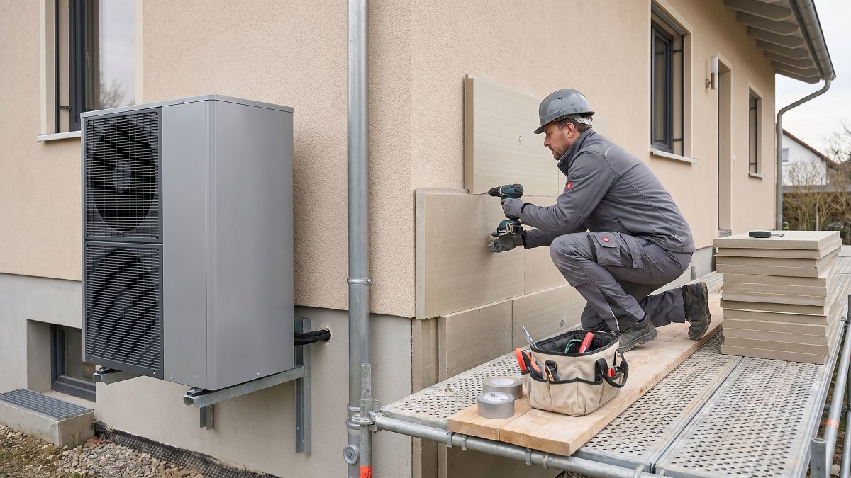 Technicien installant des panneaux d'isolation thermique par l'extérieur sur une maison