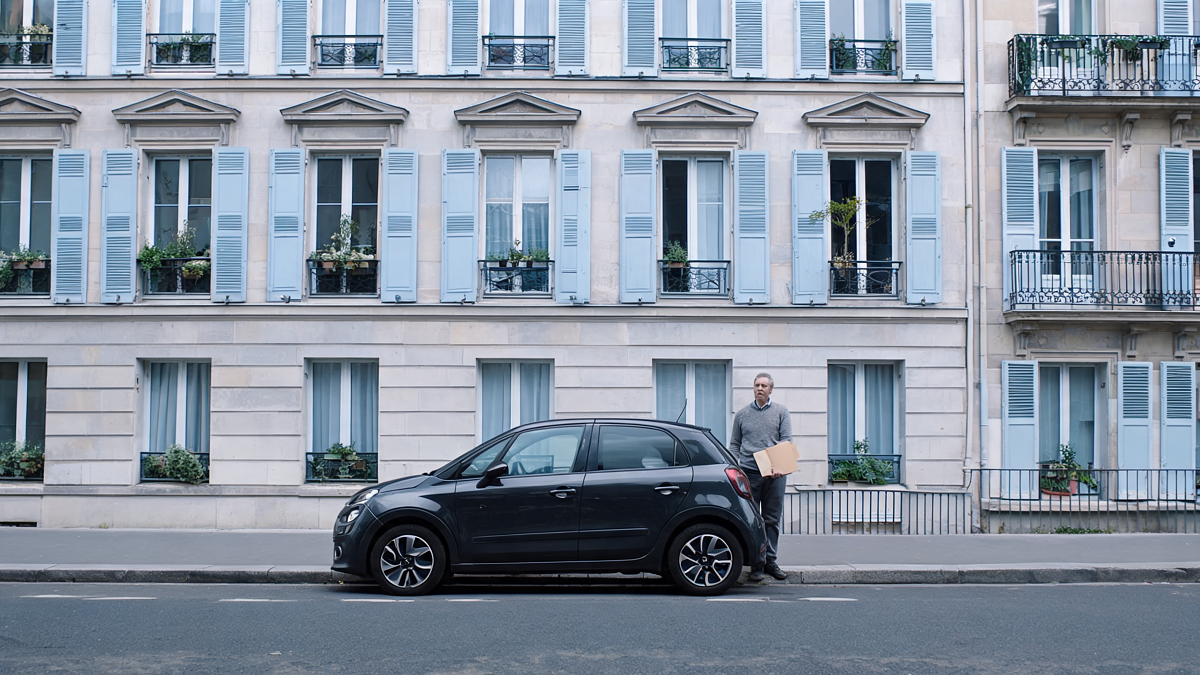 Voiture compacte garée devant un immeuble, illustrant dix ans de détention et d'assurance