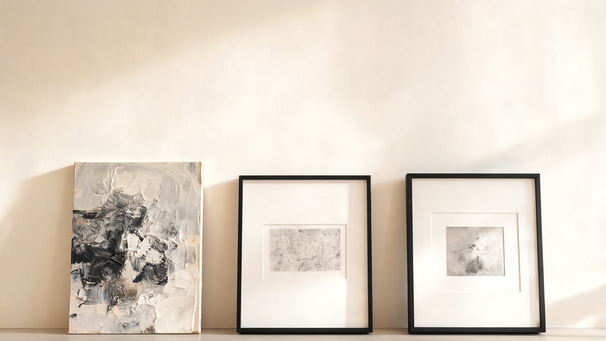Une peinture, une œuvre sur papier et une estampe encadrée comparées contre un mur clair