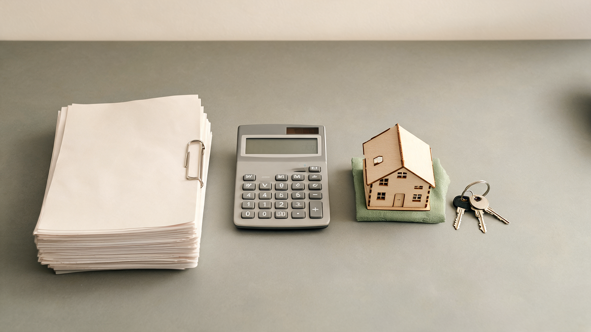 Dossier d'aides à la rénovation, documents, calculatrice et maquette de maison sur un bureau