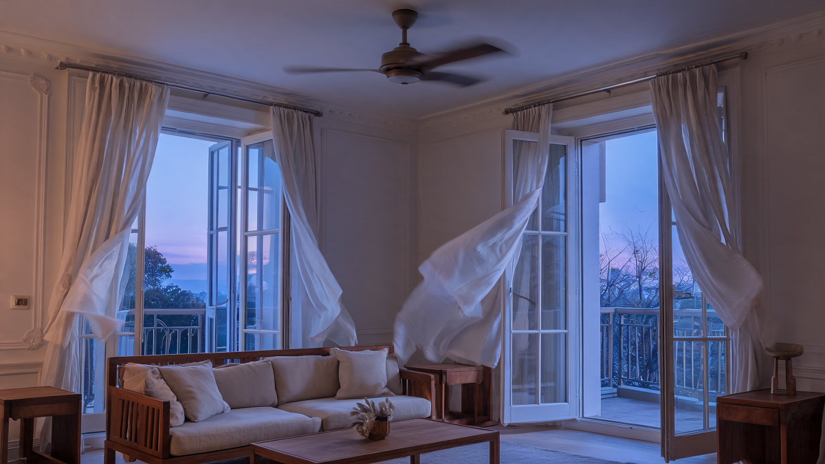 Salon aéré au crépuscule avec ventilateur de plafond et fenêtres ouvertes pour la ventilation nocturne traversante