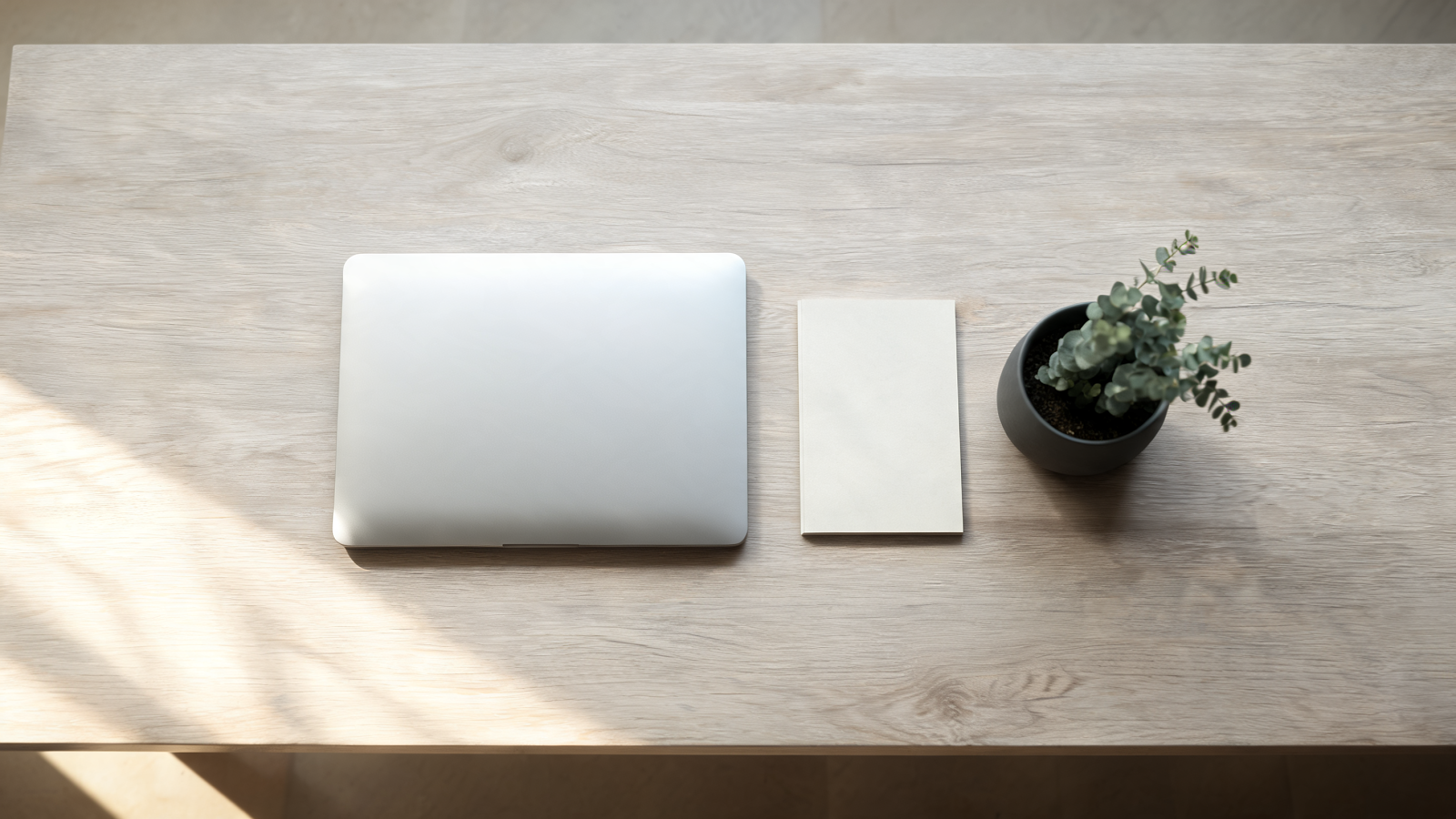 Poste de travail minimaliste avec un ordinateur portable fermé sur un bureau en chêne clair