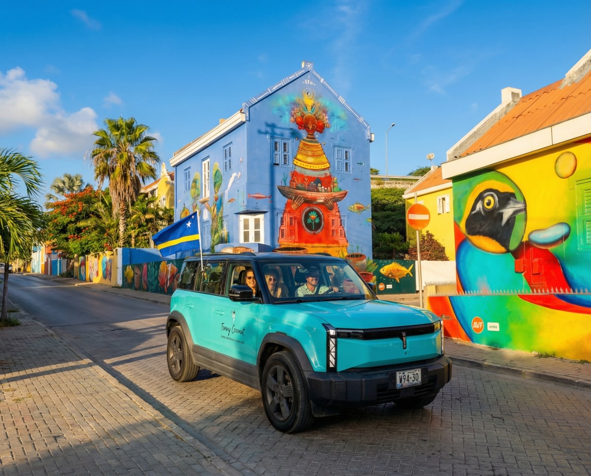 A turquoise Tommy Coconut vehicle on a colorful Willemstad street