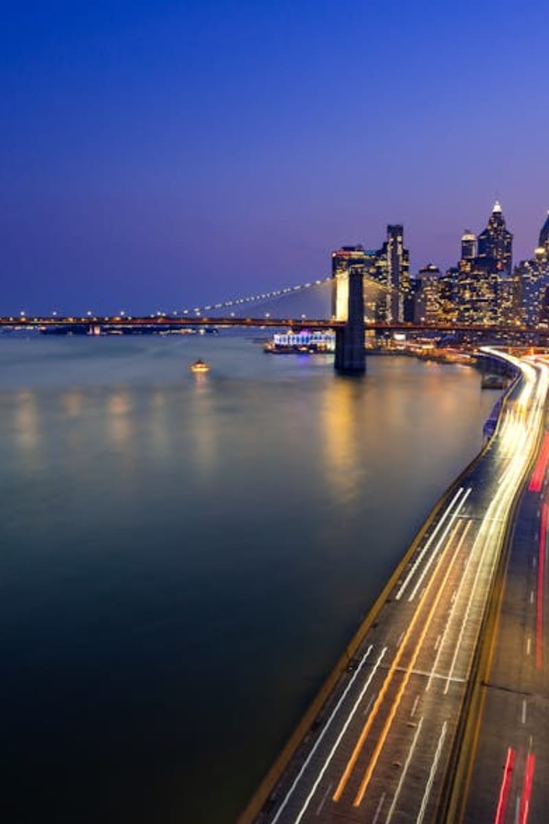 Captivating view of Brooklyn Bridge and Manhattan skyline at dusk, showcasing the vibrant lights of New York City.