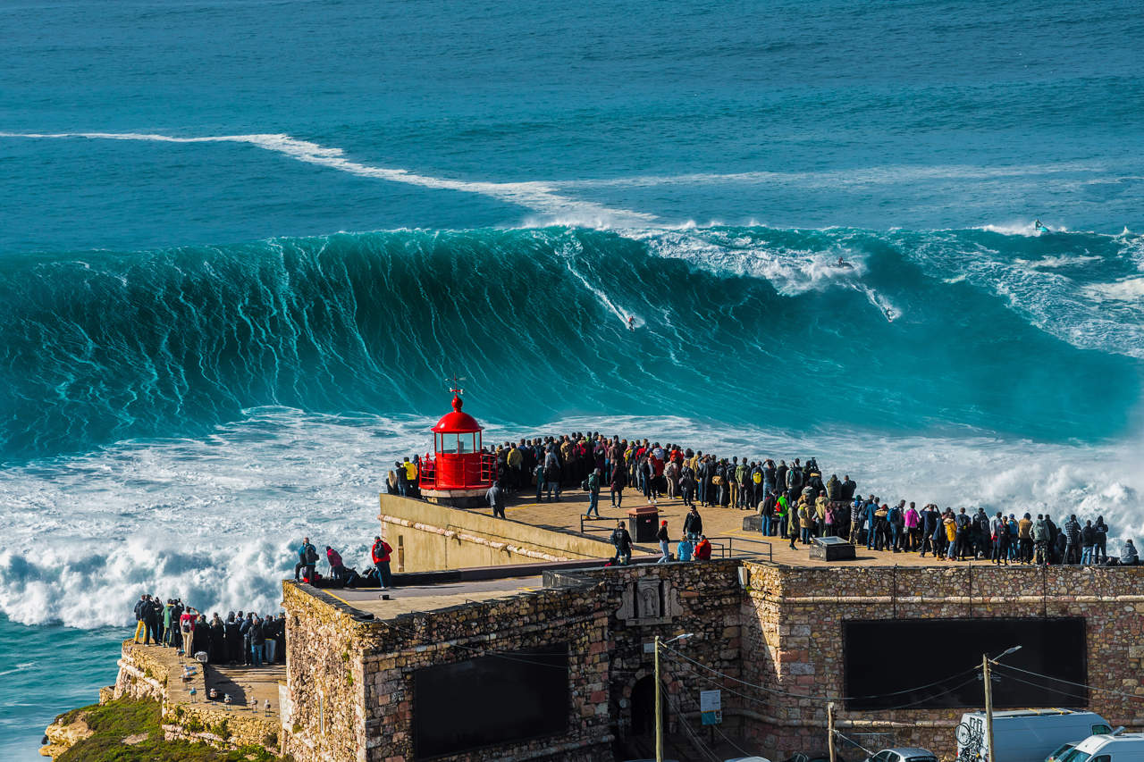 Surfista bajando una ola del tamaño de un edificio.