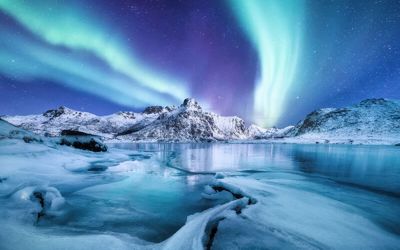 Cielo nocturno con auroras verdes sobre fiordos.