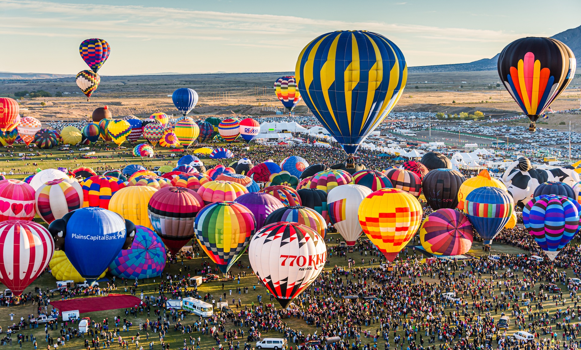 Cientos de globos de colores sobre el desierto al amanecer.
