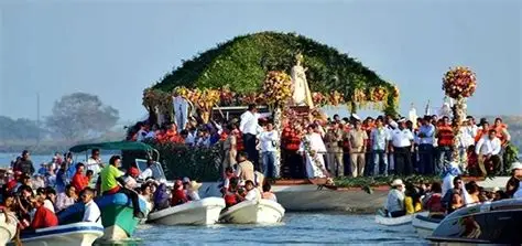 Virgen en un barco decorado en el río.
