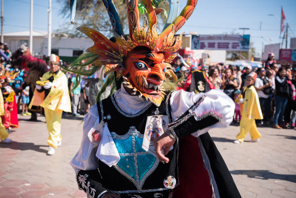 Bailarines con máscaras coloridas en el desierto.