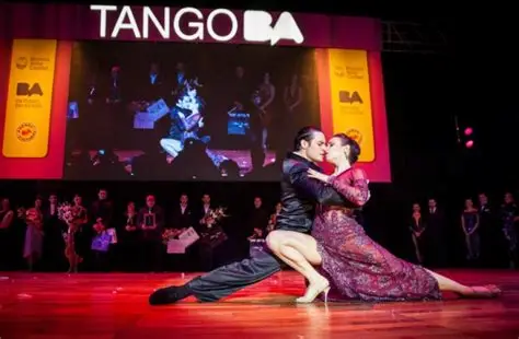 Pareja bailando tango en un escenario iluminado.