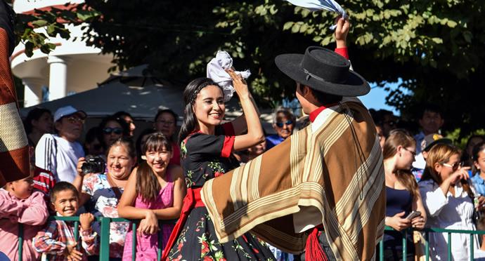 Gente bailando cueca con banderas chilenas.