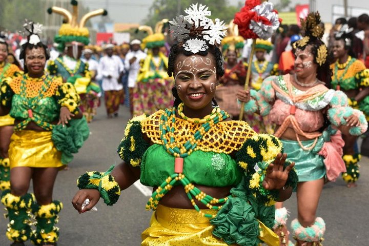 Bailarines con trajes coloridos y plumas en la calle.