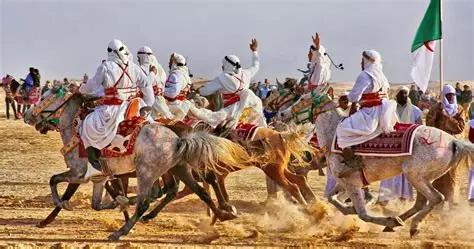 Jinetes en camello galopando por las dunas.