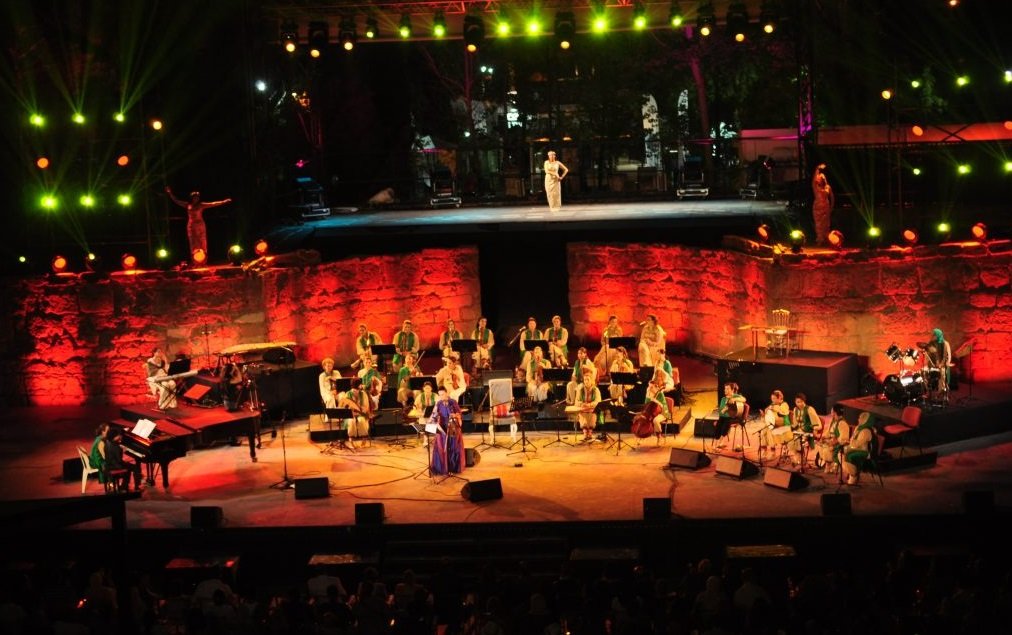 Concierto moderno en un anfiteatro romano iluminado.