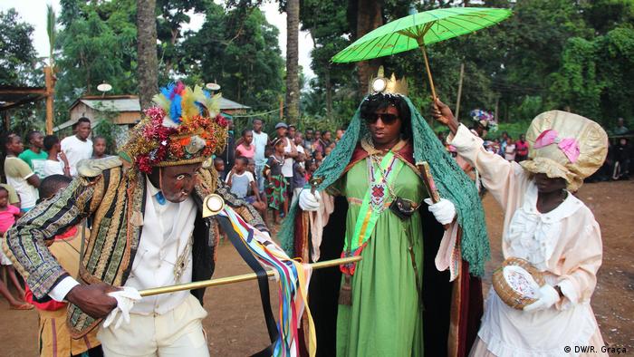 Actores con máscaras de cera y capas tradicionales.
